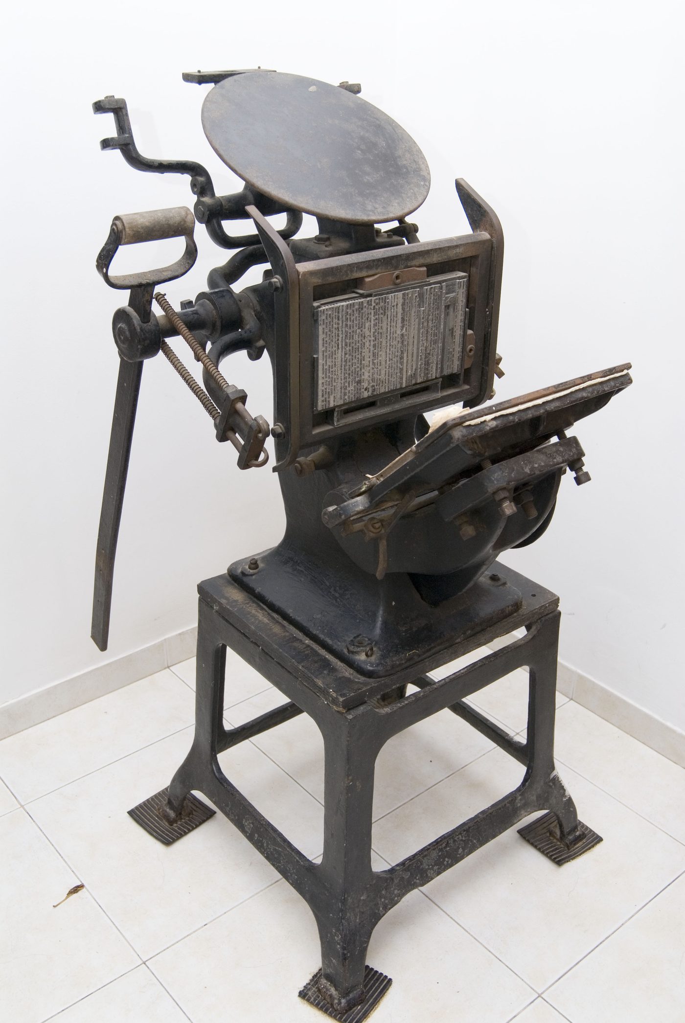 A hand-operated cast-iron platen press, with no people in the frame.
